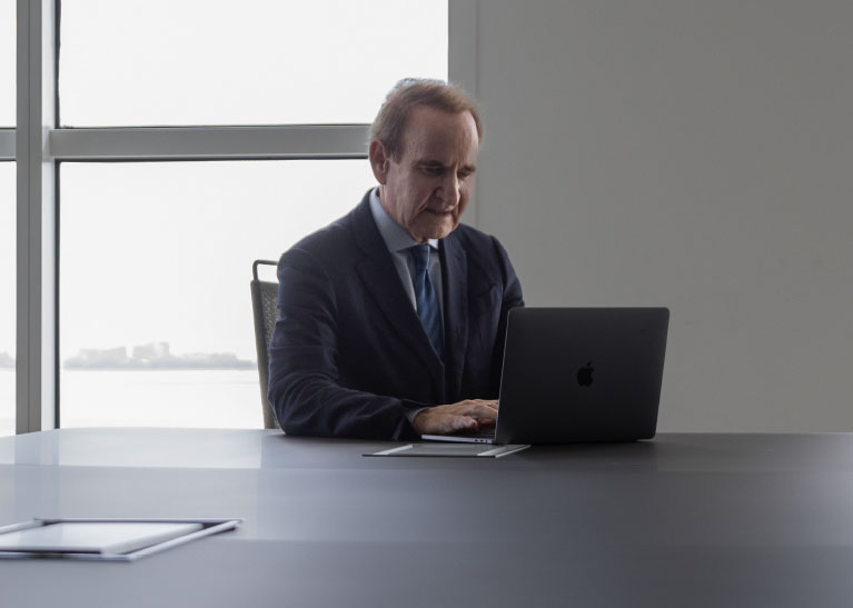 A man sat at a table using a laptop computer.